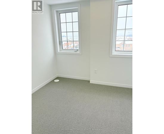 A room with a window and a grey carpet.