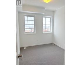 A room with a carpeted floor and two windows.