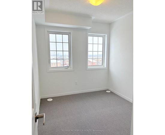 A room with a carpeted floor and two windows.