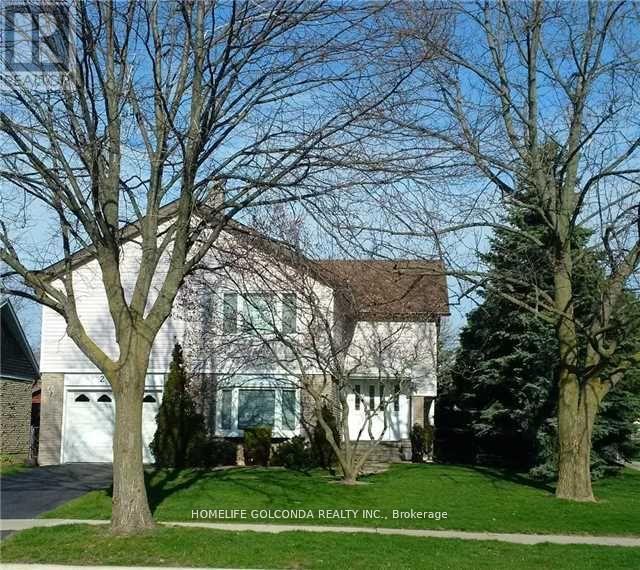 A white house with a brown roof and a tree in front.