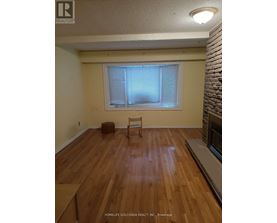 A room with wooden flooring and a window with blinds.