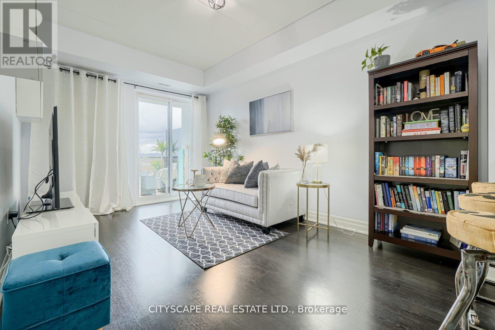 A living room with a white sofa, a coffee table, a TV, a bookshelf, and a window with white curtains.