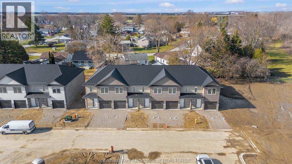 A real estate company's logo is watermarked on an aerial photo of a residential area with houses and construction.