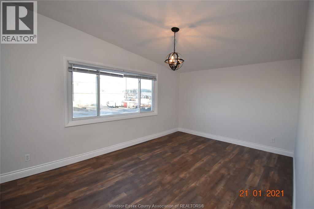 A room with wooden flooring and a chandelier hanging from the ceiling.