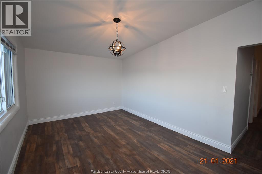 A room with wooden floors and a light fixture hanging from the ceiling.