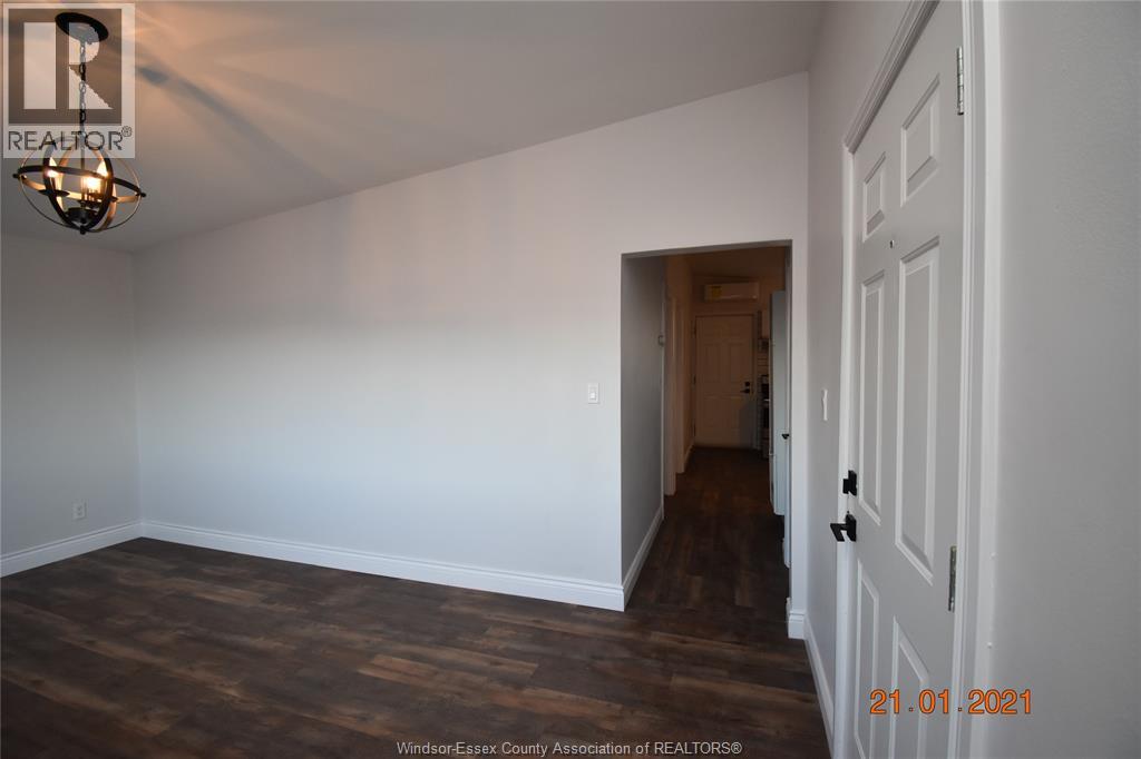 A room with a wooden floor and white walls, with a door on the right side.
