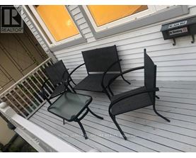 Two black metal chairs are on a white porch.