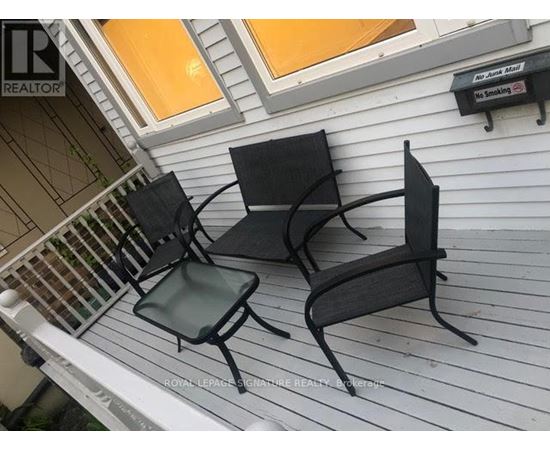 Two black metal chairs are on a white porch.
