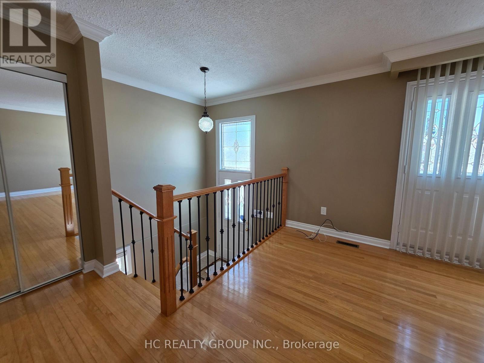 A room with wooden floors and a staircase with a railing.