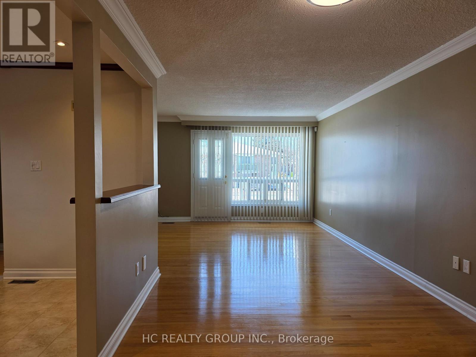 A room with a sliding glass door and wooden flooring.