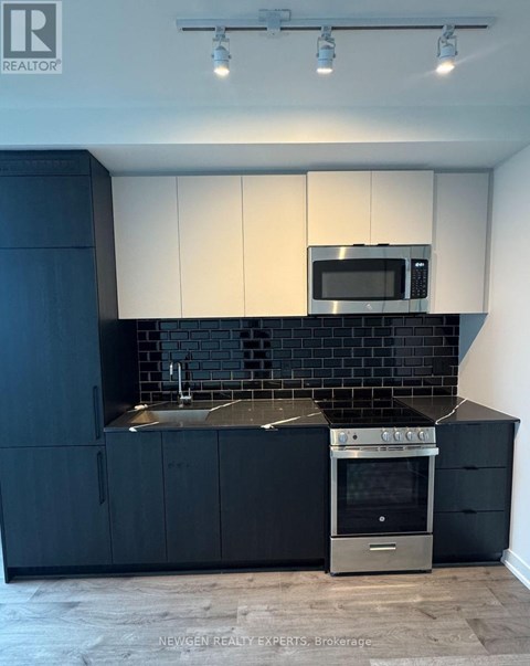 A modern kitchen with black and white cabinets and a stainless steel oven.
