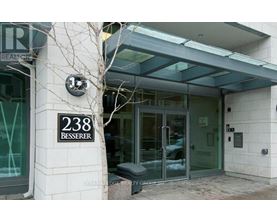 The entrance to a building with a glass door and a bench in front.