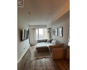 A living room with a couch, a rug, and a large window.