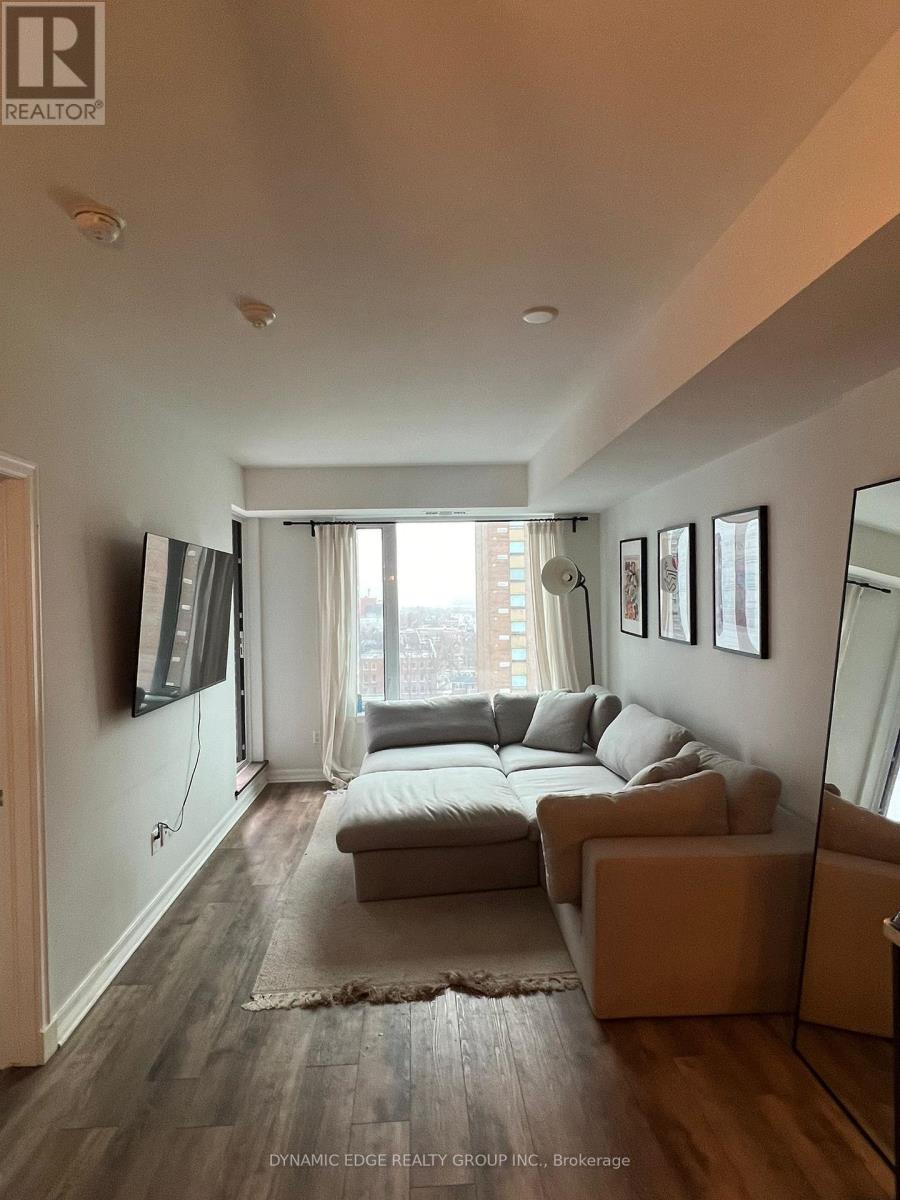 A living room with a grey couch and a flat screen TV mounted on the wall.