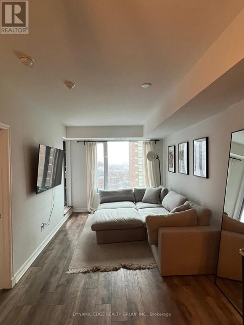 A living room with a grey couch and a flat screen TV mounted on the wall.