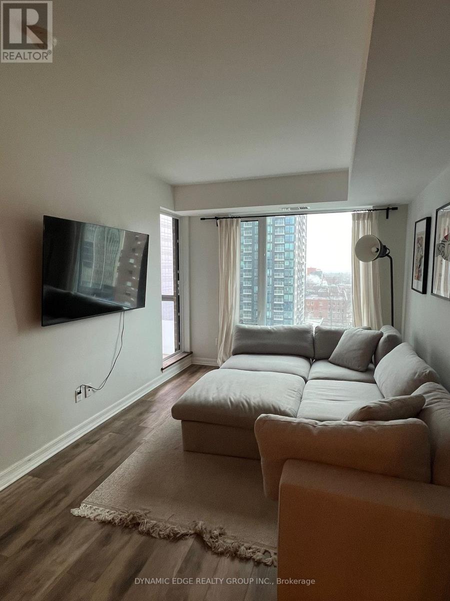 A living room with a couch, a flat screen TV and a window with curtains.