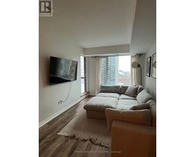 A living room with a couch, a flat screen TV and a window with curtains.