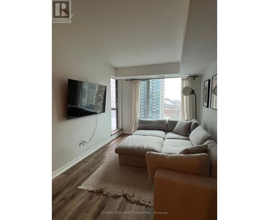 A living room with a couch, a flat screen TV and a window with curtains.