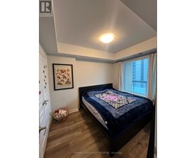 A bedroom with a bed and a framed picture on the wall.