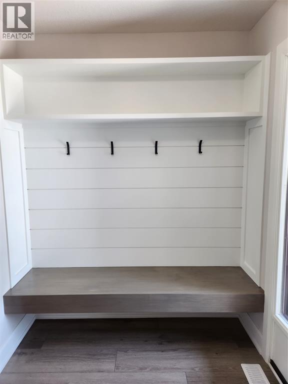 A white mudroom with a bench and coat hooks.