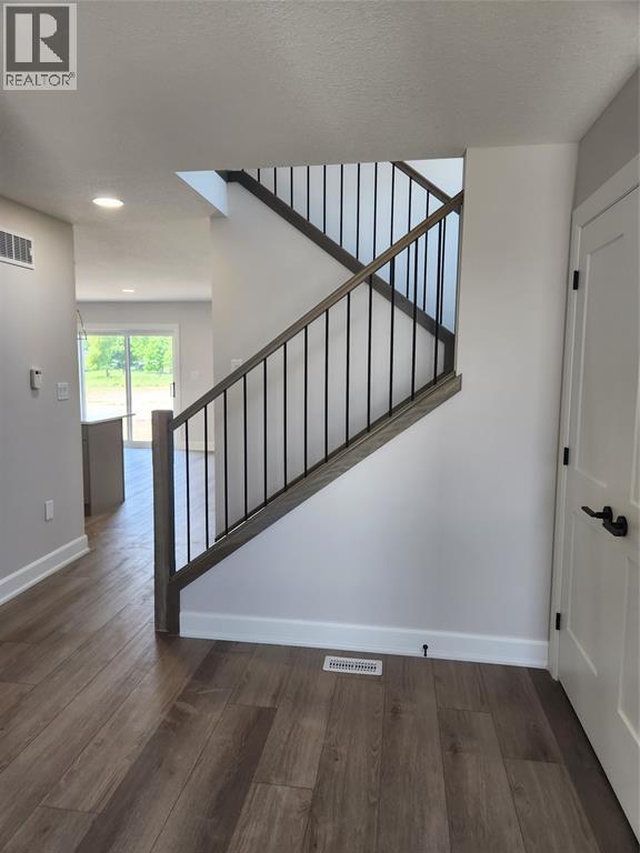 A wooden staircase with a metal railing leads to a second floor.