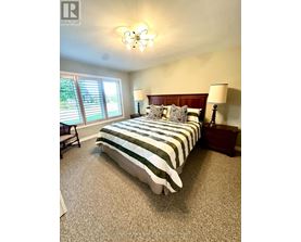A bedroom with a bed, nightstands, and a window with blinds.