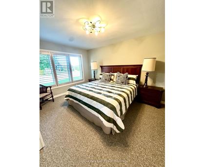 A bedroom with a bed, nightstands, and a window with blinds.