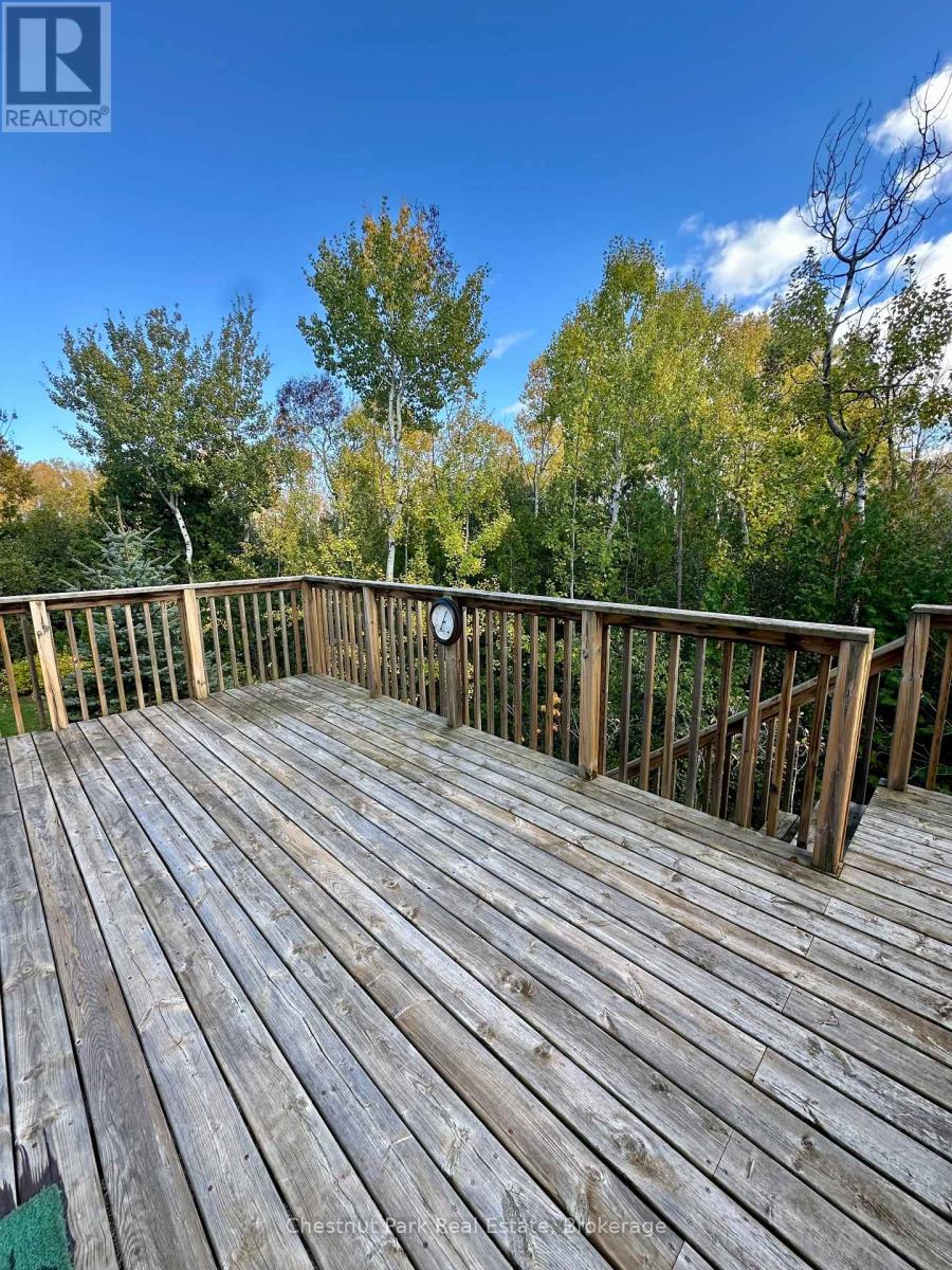A wooden deck with a railing and trees in the background.