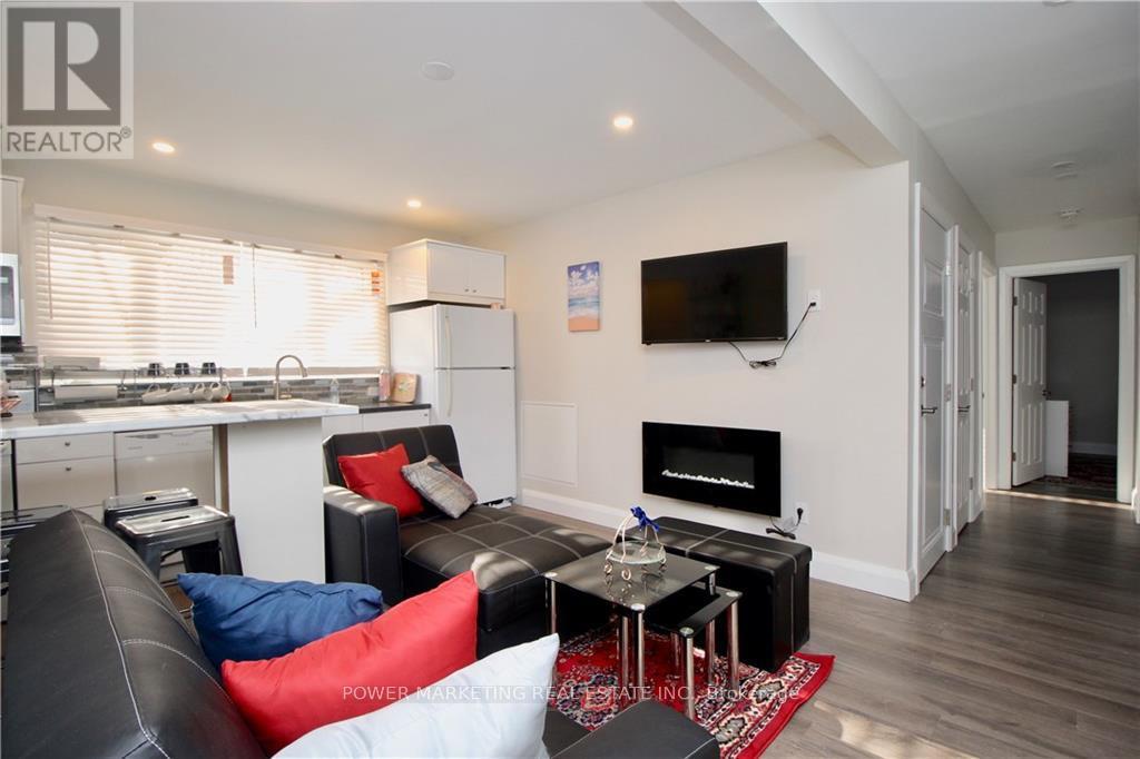 A living room with a black couch and a television mounted on the wall.