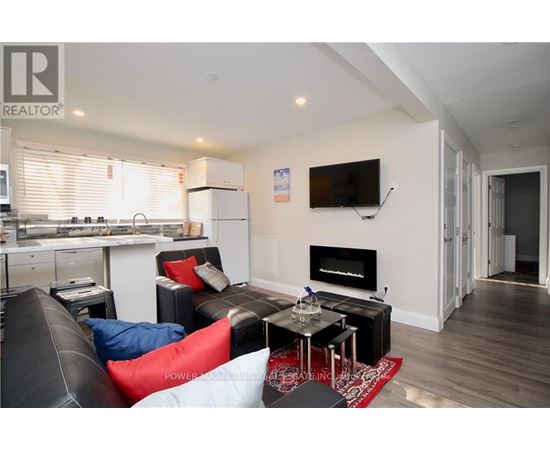 A living room with a black couch and a television mounted on the wall.