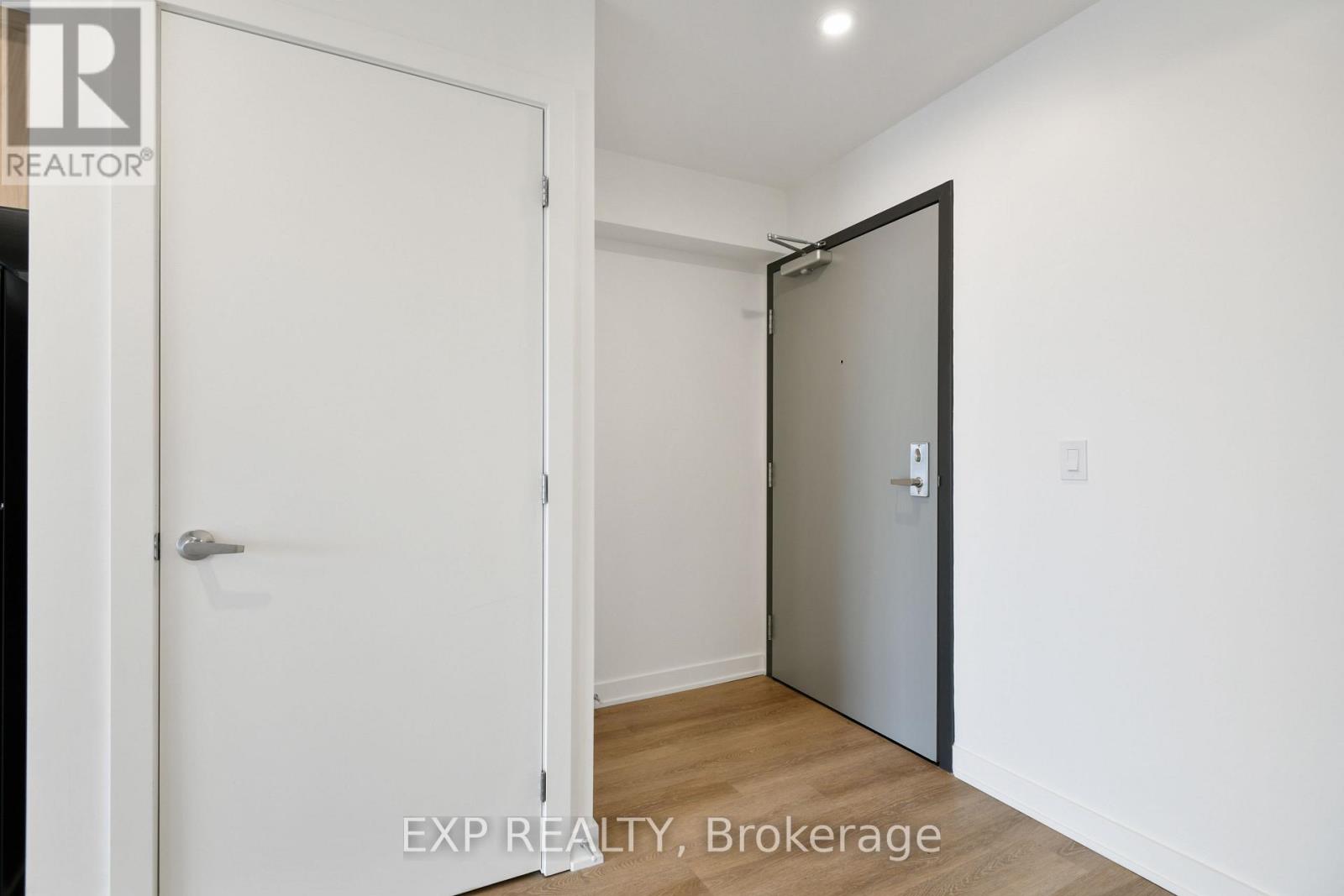 A white door is open to a room with a white wall and a wooden floor.