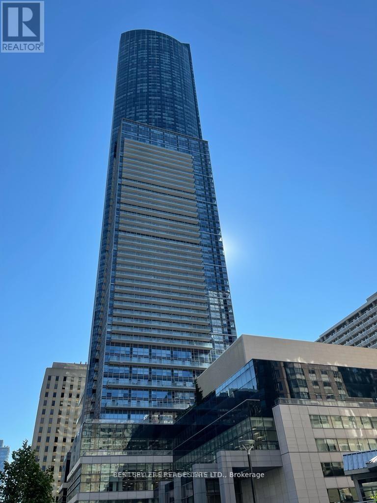 A tall building with a glass facade stands in front of a smaller building with a sign that reads "REALTOR".