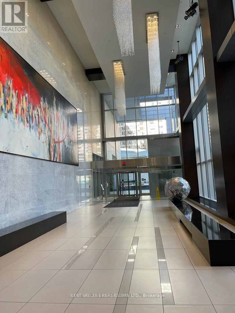 A hallway with a large painting on the wall and a glass wall on the other side.