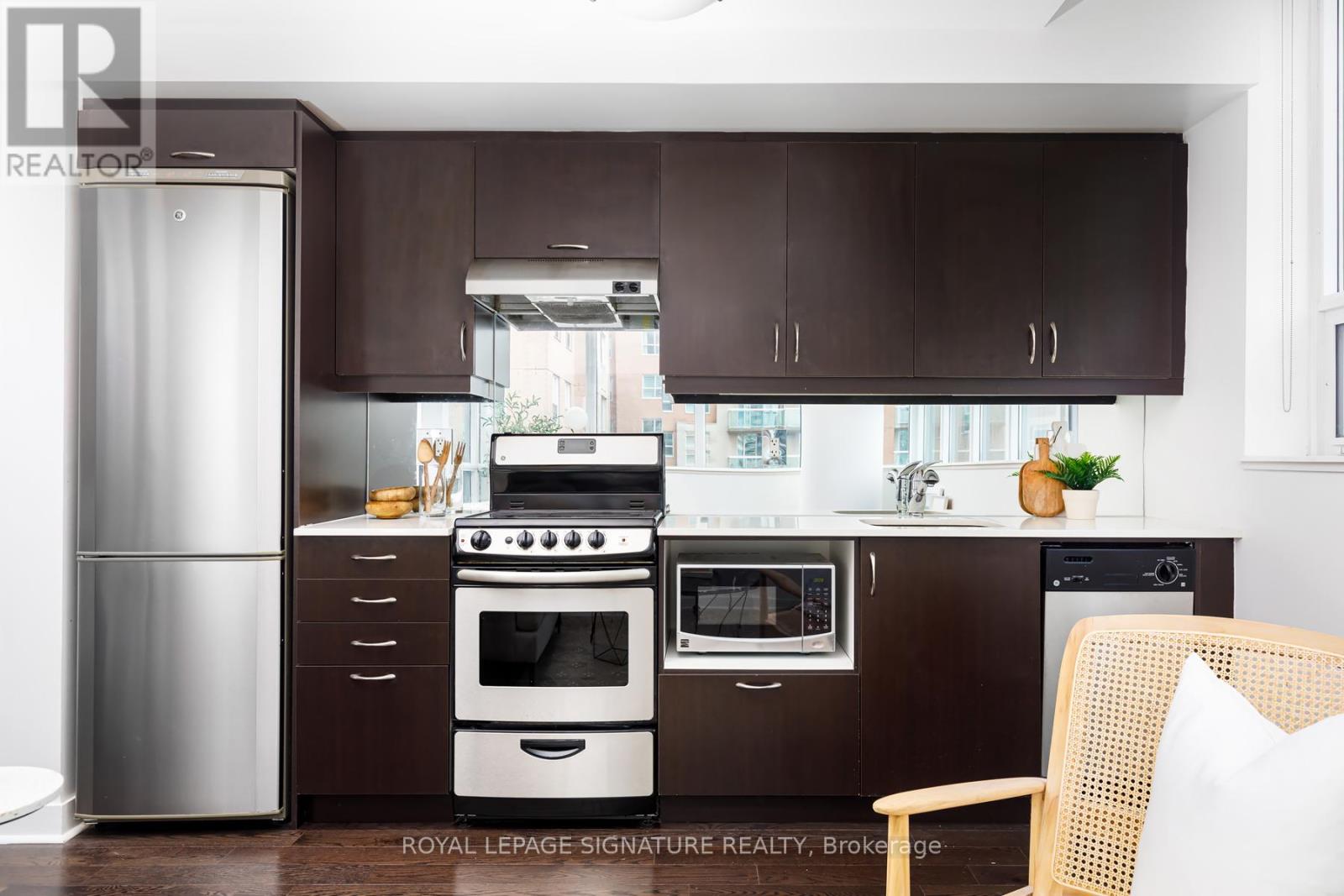 A modern kitchen with dark brown cabinets and stainless steel appliances.