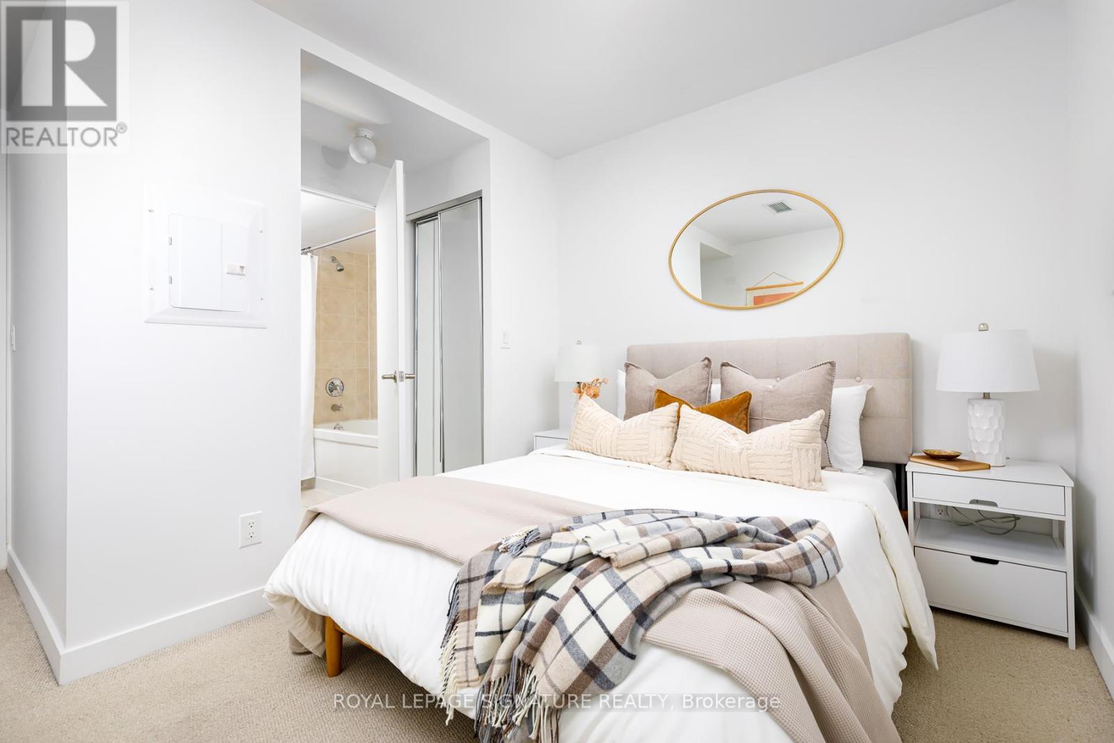 A bedroom with a bed, nightstand, and a mirror on the wall.