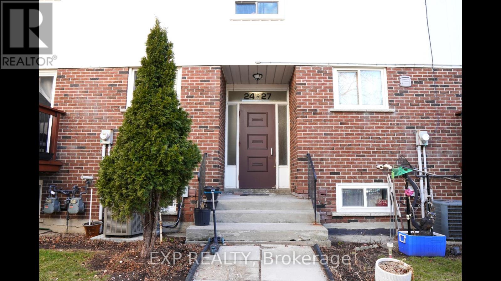 A brick house with a brown door and a small tree in front.