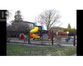 A playground with a yellow slide and a black fence.