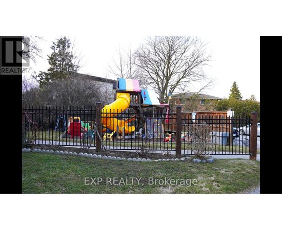 A playground with a yellow slide and a black fence.