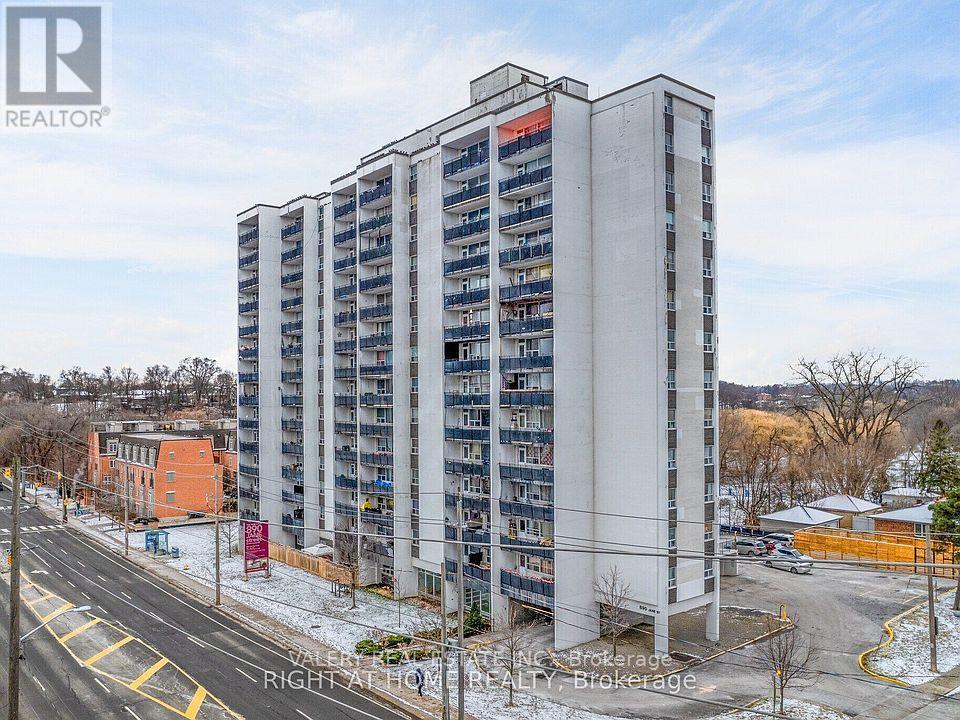 A tall residential building with a parking lot in front.