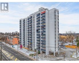 A tall residential building with a parking lot in front.