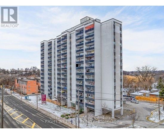 A tall residential building with a parking lot in front.