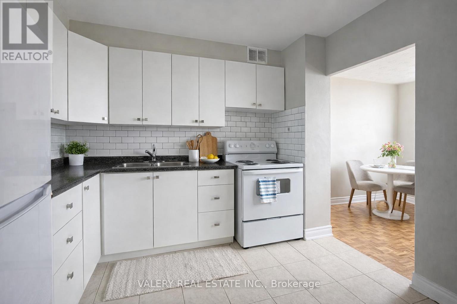 A kitchen with white cabinets and a black countertop.
