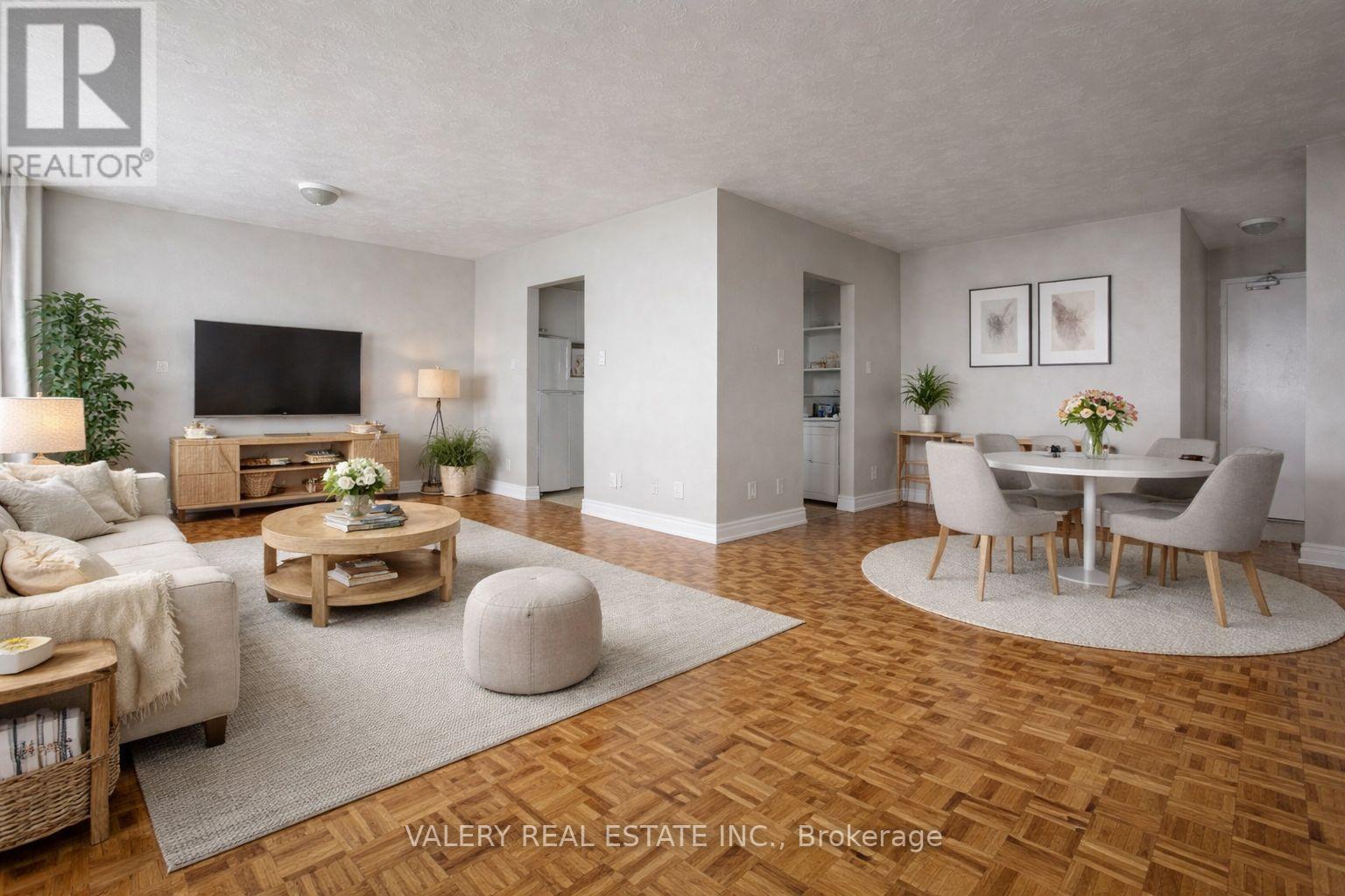A living room with a wooden floor and a television on the wall.