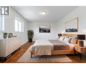 A bedroom with a bed, nightstand, and dresser.