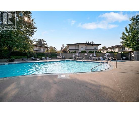 A swimming pool in a residential area with houses in the background.