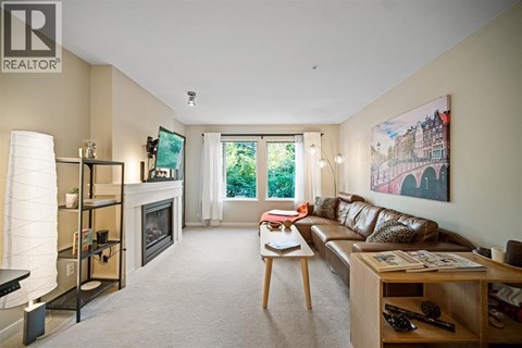 A living room with a couch, a fireplace, and a painting on the wall.