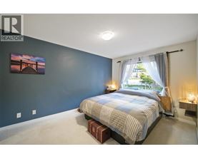 A bedroom with a bed, nightstands, and a painting on the wall.