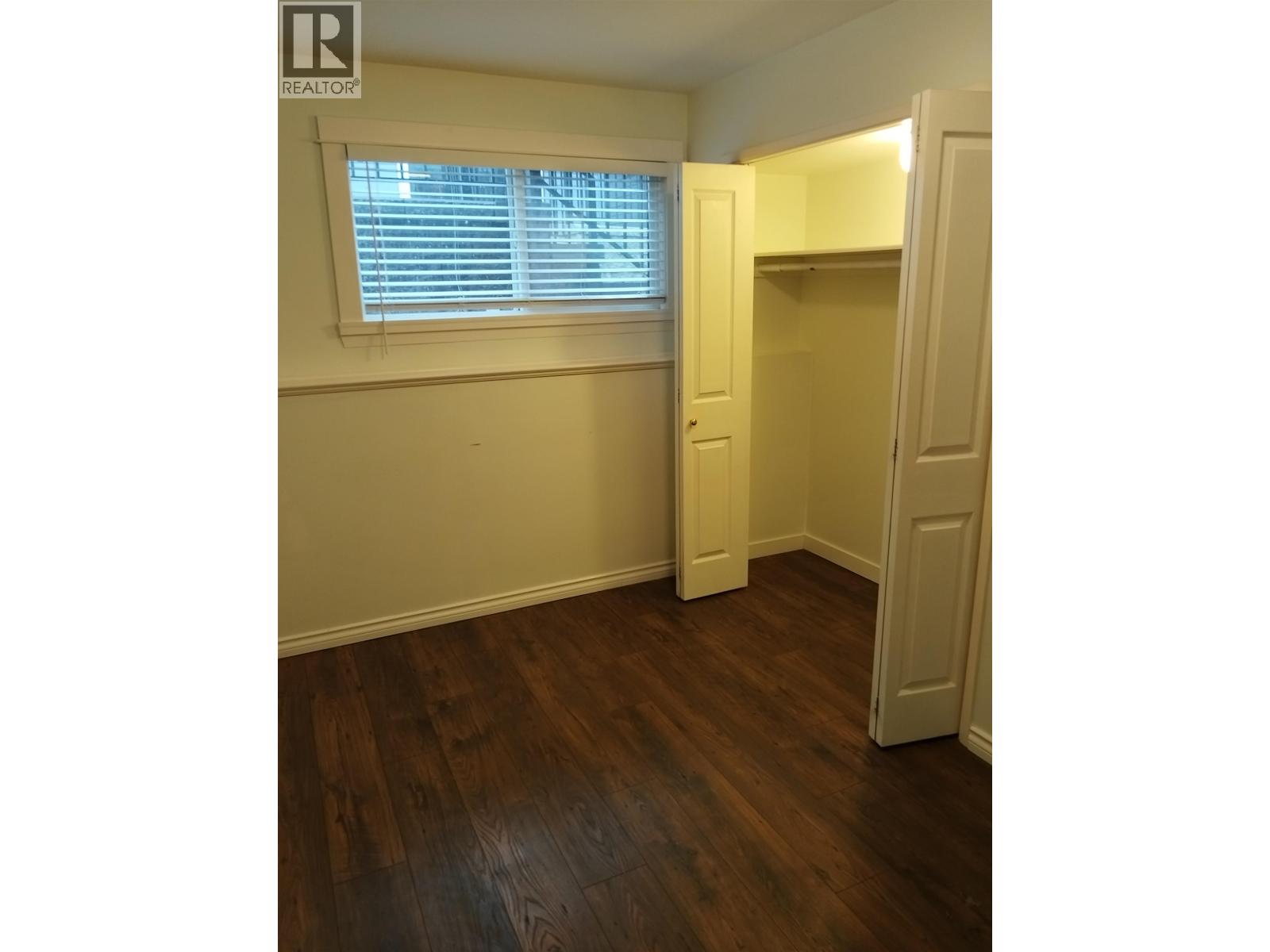 A room with wooden floors and a window with blinds.