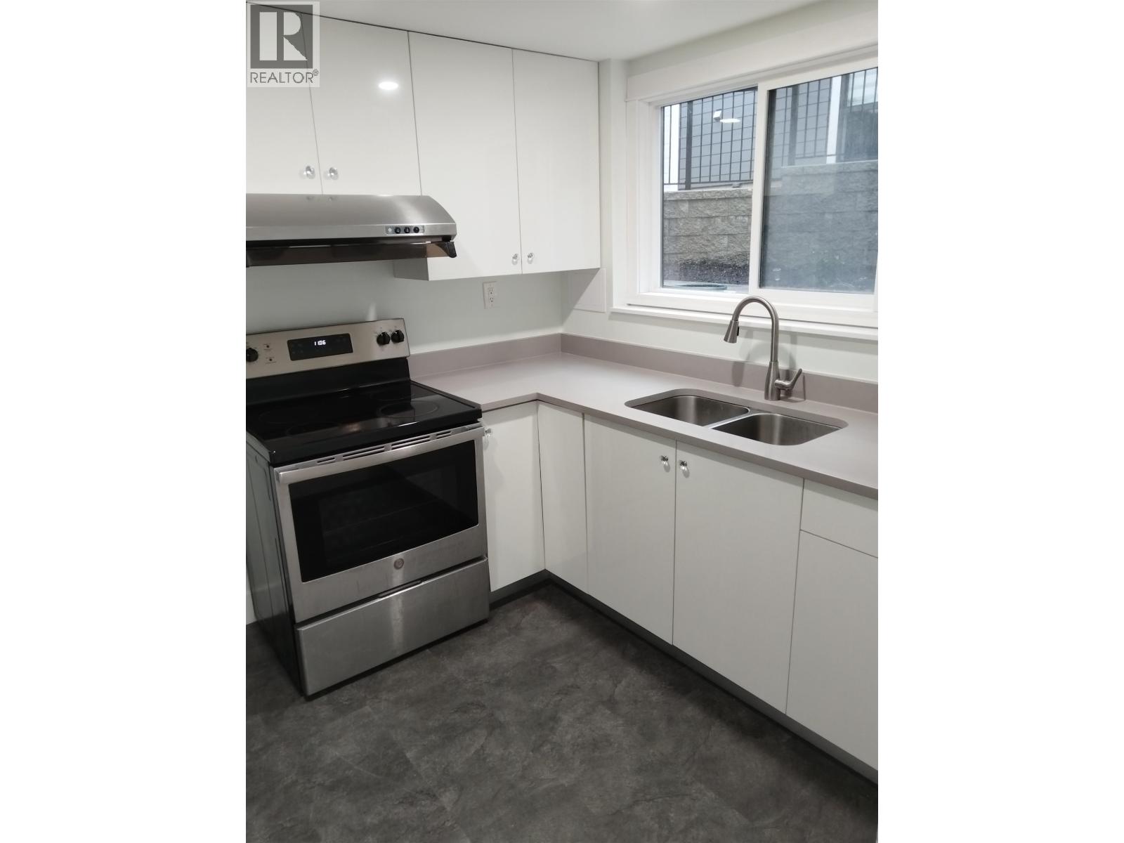 A modern kitchen with a stainless steel oven and white cabinets.