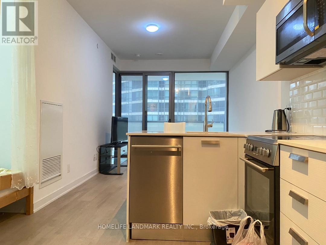 A kitchen with a stainless steel dishwasher and oven, and a window with a view of a cityscape.